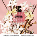 Valentino perfume bottle surrounded by flowers on a pink background